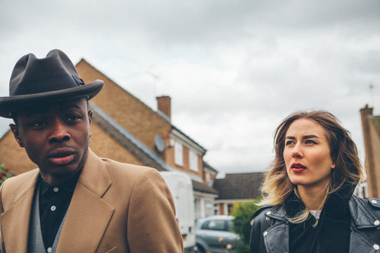 Black man and white woman walking in a suburban area