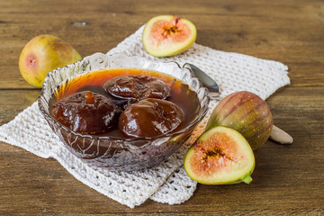  Sweet dessert. Homemade jam in a small glass vase and fresh figs on an old wooden table.