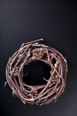 Christmas Wood Wreath with Natural Twigs and Cones.Festive decoration on a Black Background.Vintage style.Copy space.selective focus.