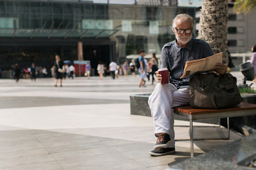 Senior Man Reading Newspaper and Drinking Coffee