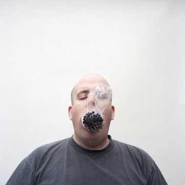 Overweight Man With Mouth Full Of Lit Cigarettes