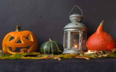 Halloween Jack o Lantern, among autumn leaves, lamps and candles
