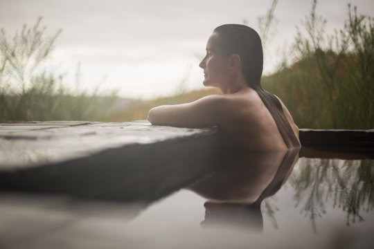 Young Woman relaxing in spa hot tub overlooking outside countryside nature garden