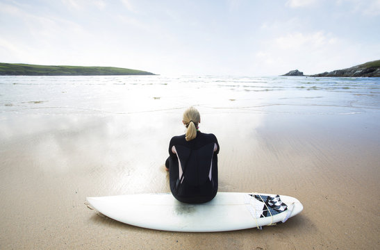 Female surfer sitting on surfboard.