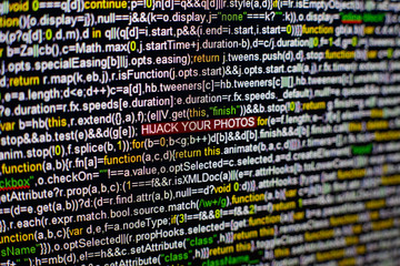 Macro photo of computer screen with program source code and highlighted HIJACK YOUR PHOTOS...