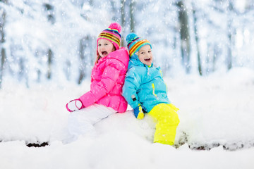 Fototapeta na wymiar Kids playing in snow. Children play outdoors in winter snowfall.