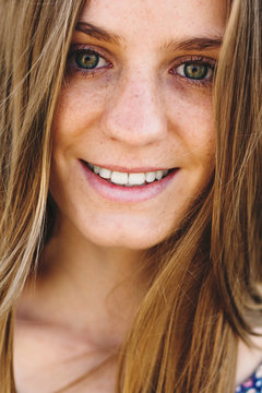 Closeup of a young freckled woman smiling looking at camera.
