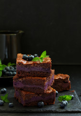 Chocolate brownies with blueberries and cream filling. Dark background.