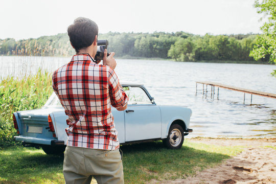 Young Man Taking  Photo of Vintage Car Parked by Lake