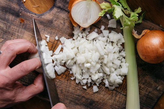 Male's hands chopping onions on a cutting board