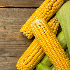 Ripe yellow sweet corn cob on a wooden table close-up