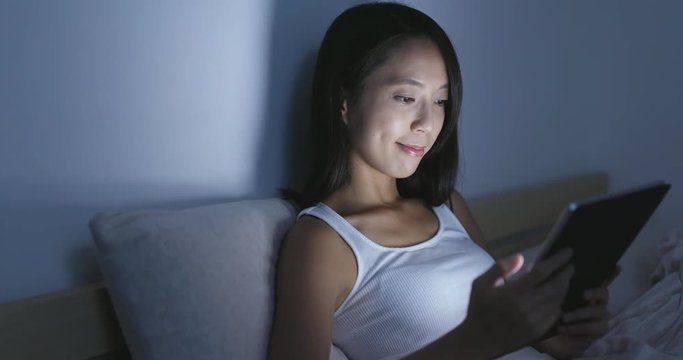 Asian Woman using tablet computer on bed