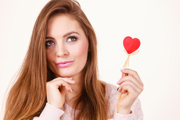 Flirty woman holding red wooden heart on stick