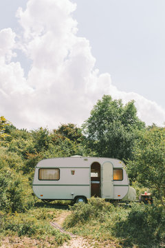 Caravan parket in the dunes in the sun in front of green bushes