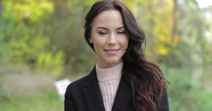 Beautiful playfully smiling woman in black jacket and polo-neck shirt posing for camera during her