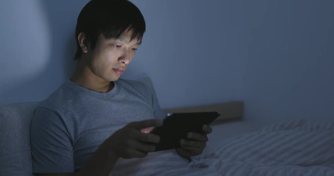 Young asian man using tablet computer at night
