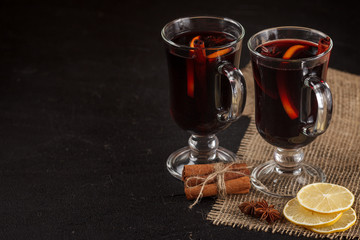 Mulled wine banner. Glasses with hot red wine and spices on dark background. Modern dark mood style.