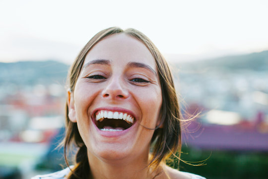 Portrait of a young woman laughing outside.