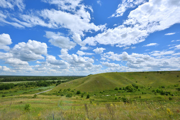 Beautiful landscape with a green hill and a blue sky with clouds