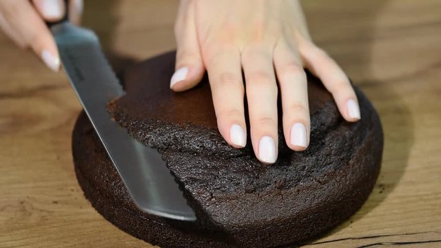 Woman cuts off the top of chocolate cake