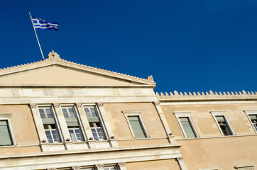 Fototapeta na wymiar Greece flag on parliament building blue sky