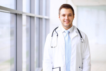 Smiling doctor waiting for his team while standing upright