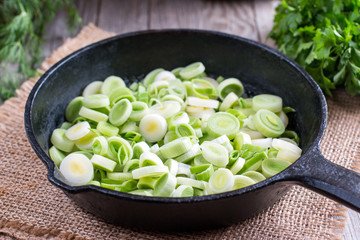 Stewing leek slices in a frying pan on a hot plate