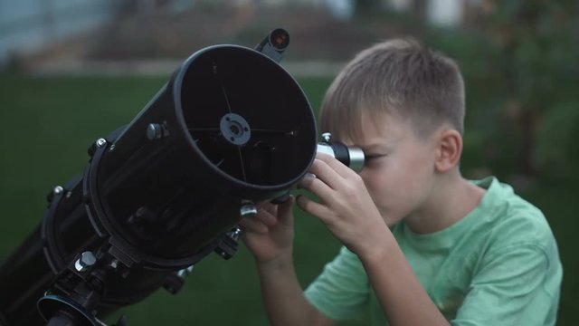 Preteen boy learn how to explore stars with telescope on backyard.