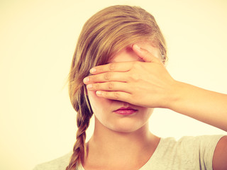 Fototapeta premium Shy teenage girl hiding face behind hand