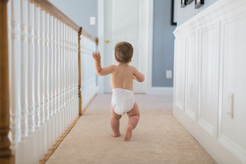 Boy toddler walking in a hallway wearing a diaper