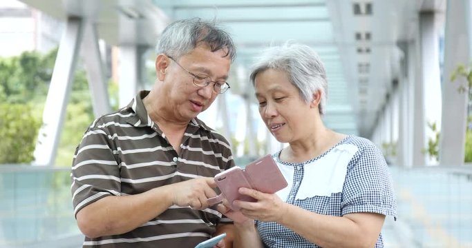 Senior retired couple using mobile phone at outdoor