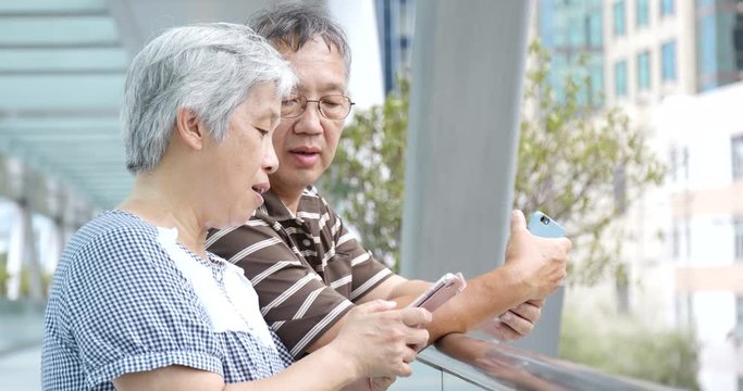 Senior couple using mobile together at outdoor