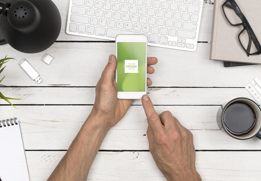 Top View Mockup of User's Hands Holding Smartphone at Desk 1