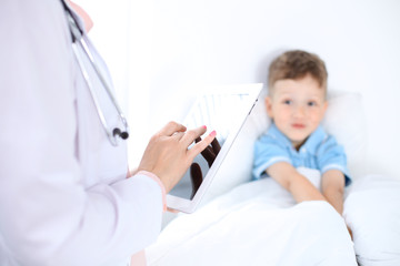 Female doctor using a digital tablet, close-up of hands. Health care concept or children's therapy 
