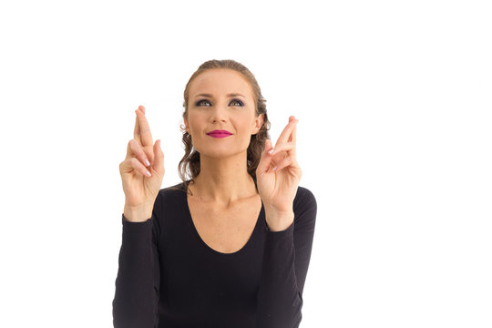 Woman uses both hands to cross her fingers. She has green eyes. Isolated on white background..