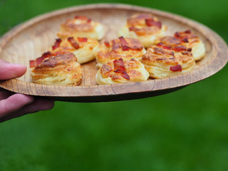 Homemade scones on wooden plate with green background.