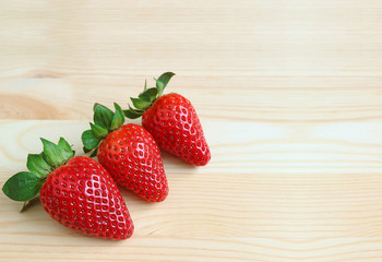 Three Bright Red Color Fresh Ripe Strawberry Fruits on Wooden Table, with Free Space for Text or Design 