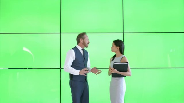  Business man & woman discussing paperwork in modern office with green screen 