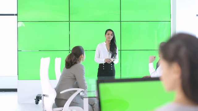 Business team in a meeting, woman interacting with green screen video wall