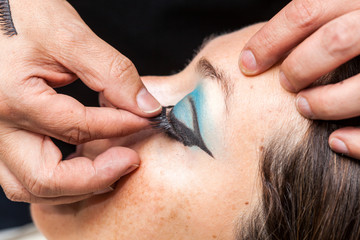 Close up of a makeup artist applying the false eyelashes to a woman