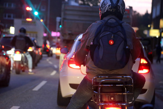 Rollerfahrer und Autofahrer warten im Berufsverkehr morgens