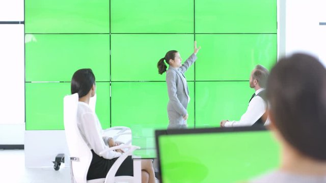  Business team in a meeting, interacting with large green screen video wall