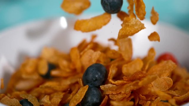 Close up slow motion cereal flakes and fresh fruit being poured into a bowl