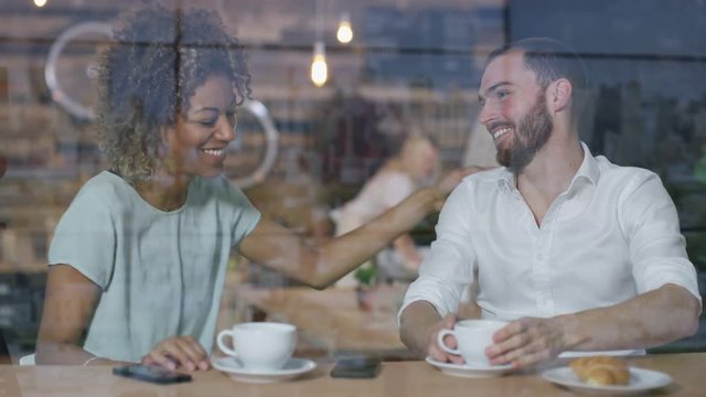 Young Couple On A Date Chatting Over Coffees In City Coffee Shop