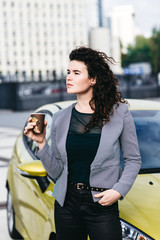 Fashionable girl standing near her car in modern city