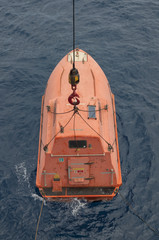 Free fall lifeboat being lifted by crane.