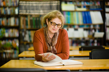 Senior woman reading book in library