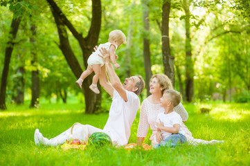 Happy family picnic. Grandfather throws up baby in the air in nature