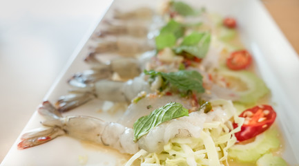 Fresh shrimp topping in fish sauce with hot and spices chili and garlic dressing on sliced cabbage. Hot and spices Thai style raw fresh shrimp salad. Thai food dish. Soft and selective focused