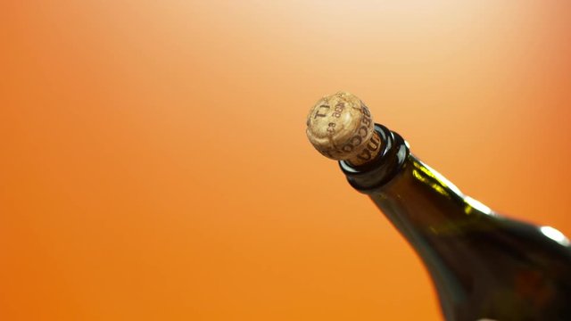  Sparkling wine cork popping on orange background, close up & in slow motion